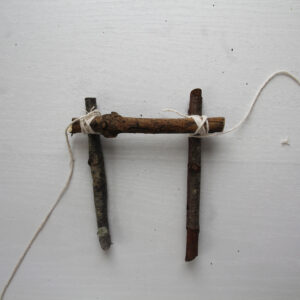 3 - Attach the first stick for the top platform on top of these base sticks. Place it at right angles about 1 cm from the end of both base sticks. Now twist the string attached to one bottom twig up and over the top stick. Keep twisting below the base stick and up and over the top stick, switching from left to right.
Then, repeat on the other side with the string attached to the second base stick.